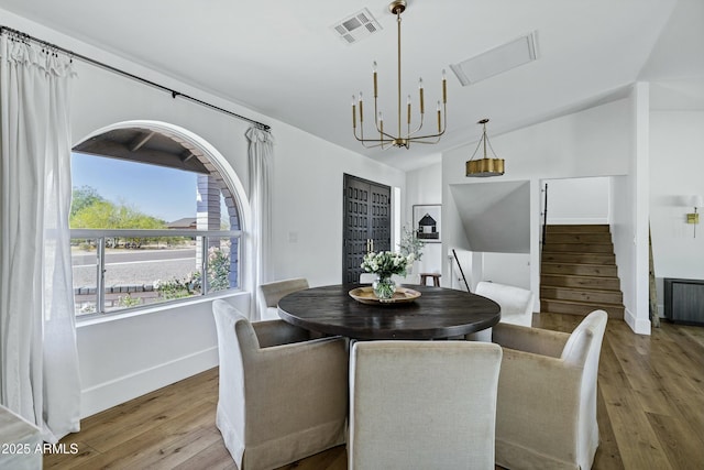 dining area with visible vents, baseboards, an inviting chandelier, wood finished floors, and stairs