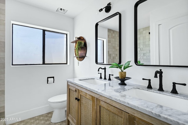 bathroom featuring toilet, double vanity, a sink, and visible vents