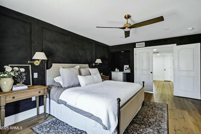 bedroom with visible vents, ceiling fan, and wood finished floors