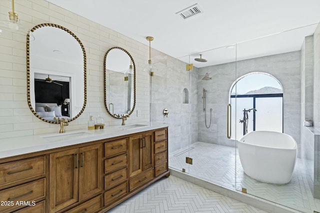 full bath featuring tile walls, visible vents, a stall shower, and a sink