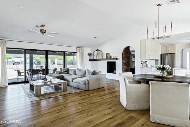 living area with arched walkways, visible vents, wood finished floors, and ceiling fan with notable chandelier