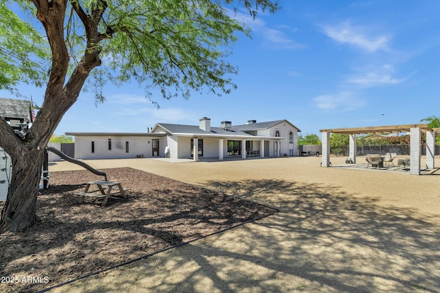 rear view of house featuring fence, a chimney, and a patio