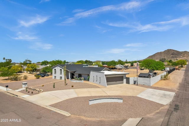 view of front facade with a mountain view, driveway, a garage, and fence