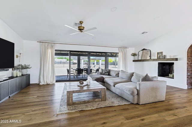living area with lofted ceiling, visible vents, ceiling fan, and wood finished floors