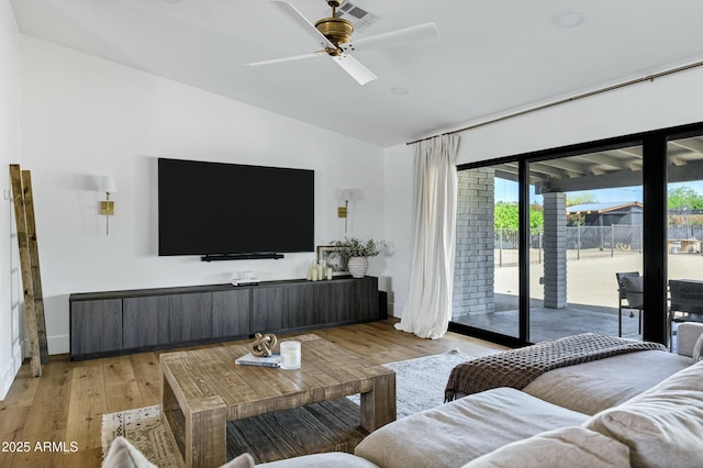 living area with lofted ceiling, light wood-style floors, ceiling fan, visible vents, and baseboards
