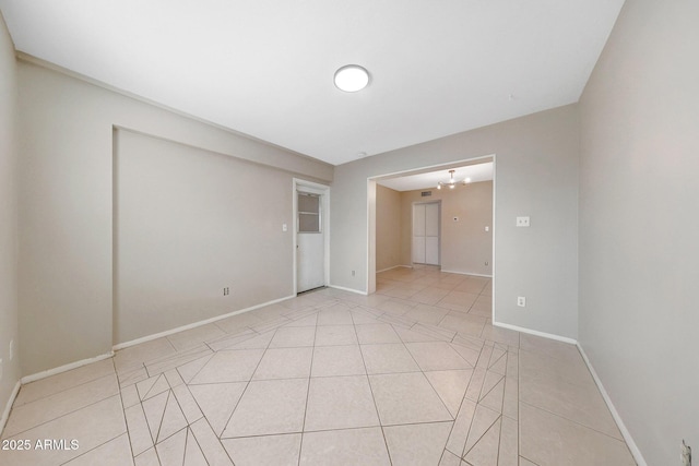 empty room featuring baseboards and light tile patterned floors