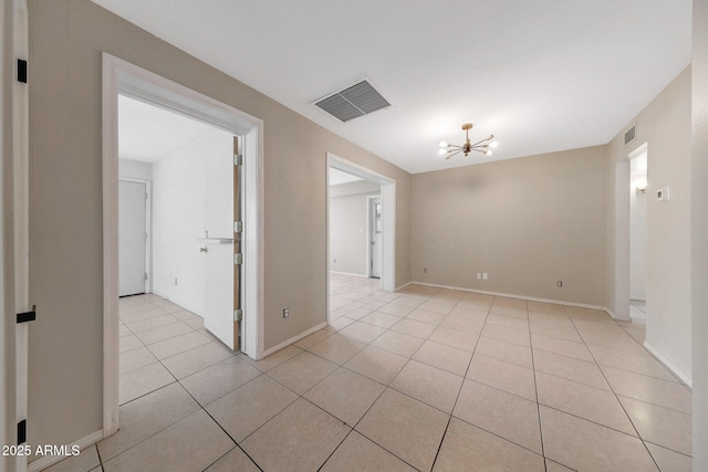 empty room featuring light tile patterned floors, baseboards, visible vents, and an inviting chandelier