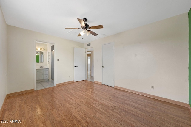 unfurnished bedroom featuring visible vents, light wood-style flooring, ensuite bathroom, a ceiling fan, and baseboards