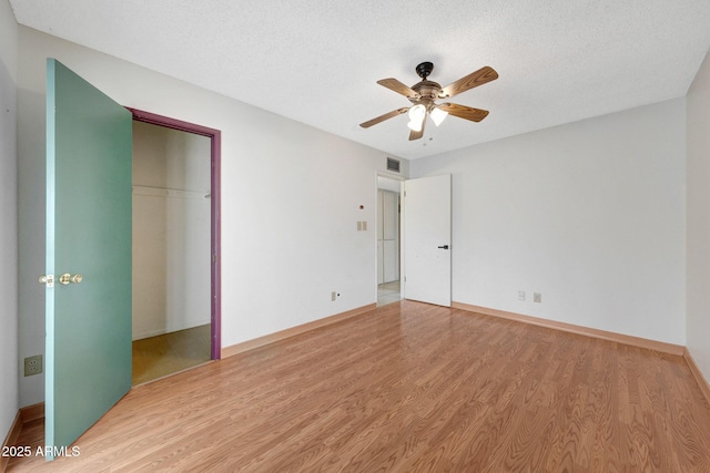 unfurnished bedroom featuring a textured ceiling, light wood finished floors, a closet, and visible vents