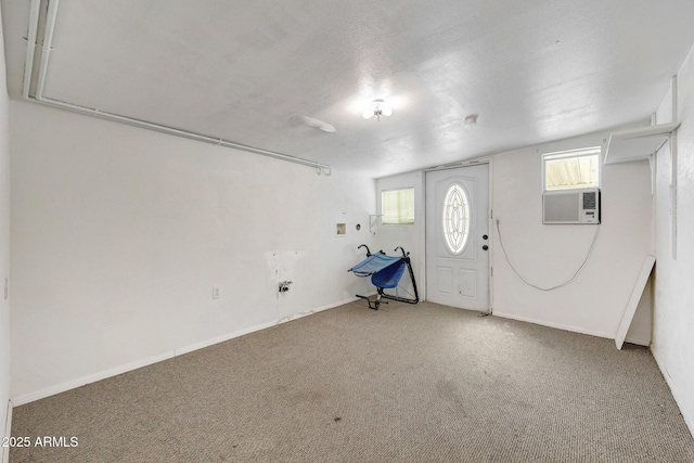 below grade area featuring a textured ceiling, carpet, cooling unit, and baseboards