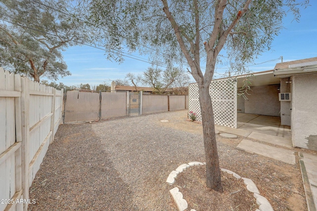 view of yard with a patio area, a fenced backyard, and a gate