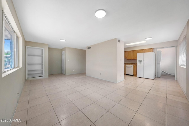 unfurnished living room with light tile patterned floors, baseboards, visible vents, and built in features