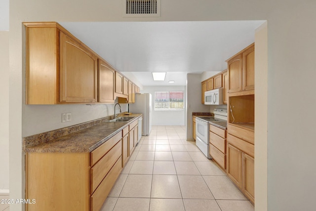 kitchen featuring light tile patterned floors, white appliances, a sink, visible vents, and dark countertops