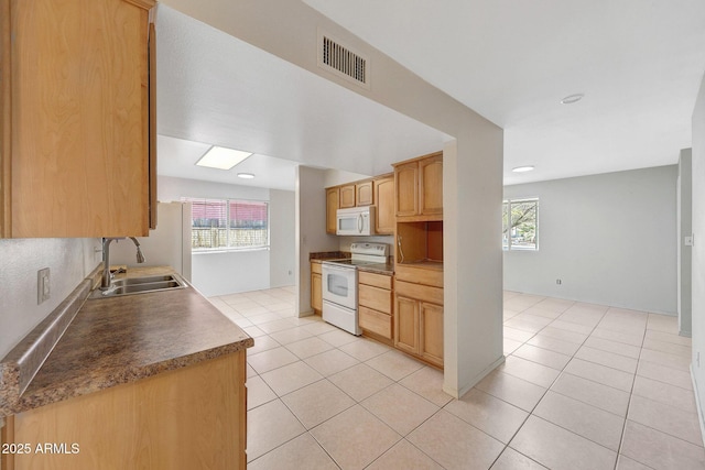 kitchen featuring light tile patterned floors, visible vents, light brown cabinetry, a sink, and white appliances