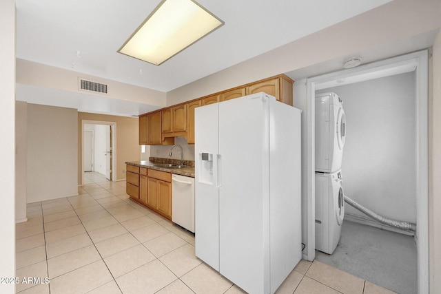 kitchen with light tile patterned flooring, white appliances, a sink, visible vents, and stacked washer and clothes dryer