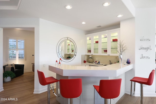 bar with hardwood / wood-style floors, white cabinetry, and backsplash