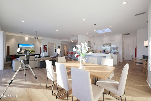 dining area featuring a skylight, light hardwood / wood-style flooring, and ceiling fan