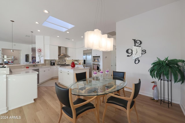 dining space featuring a skylight, sink, and light hardwood / wood-style floors