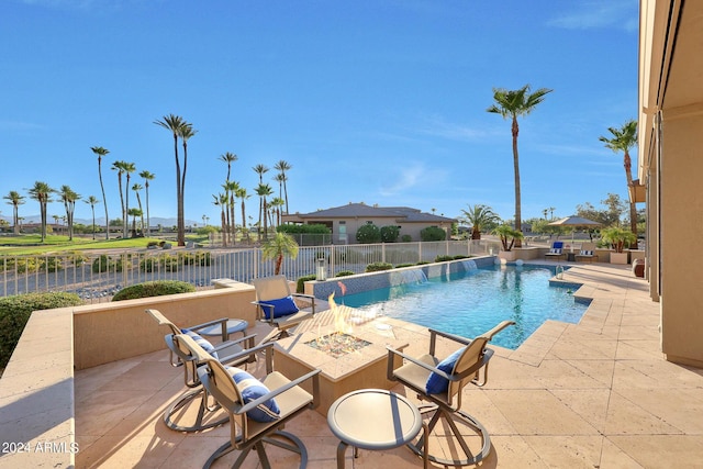 view of pool featuring a patio area, pool water feature, and a fire pit