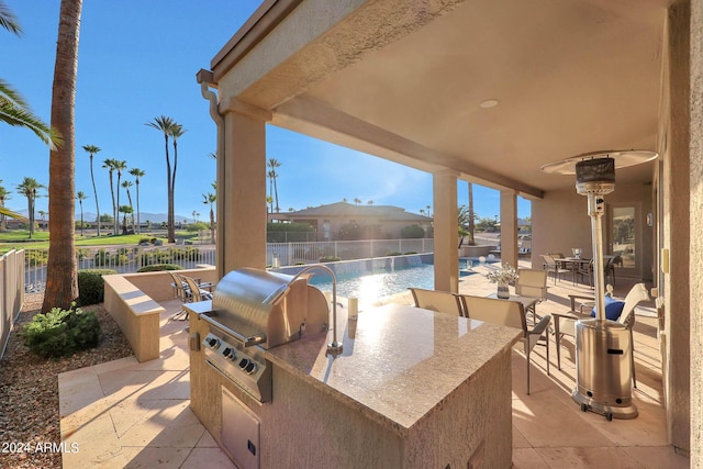 view of patio with pool water feature, a grill, a fenced in pool, and exterior kitchen