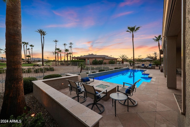 pool at dusk featuring a fire pit and a patio