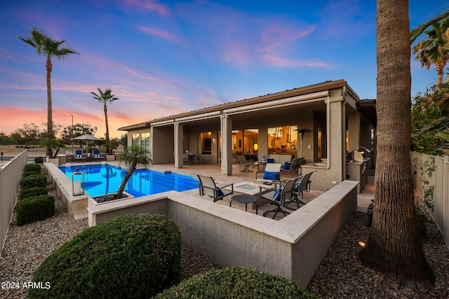 pool at dusk featuring a patio