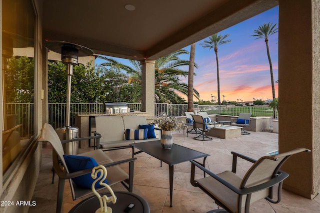 patio terrace at dusk featuring area for grilling and an outdoor living space with a fire pit