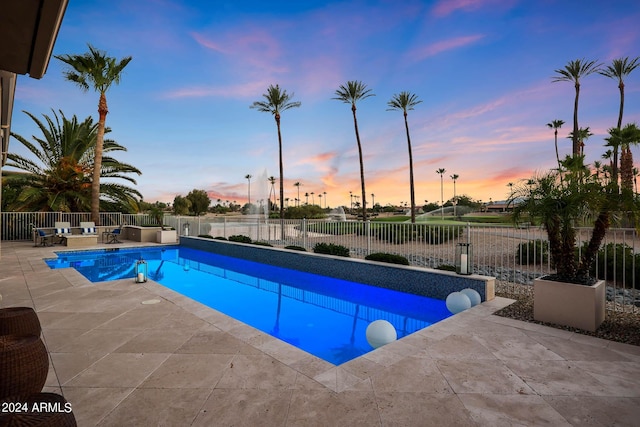 pool at dusk featuring a patio