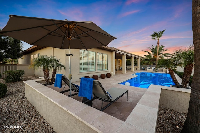 pool at dusk featuring a patio