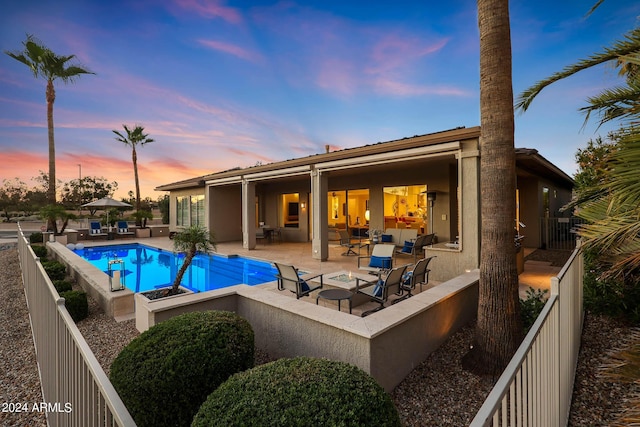 pool at dusk featuring a patio