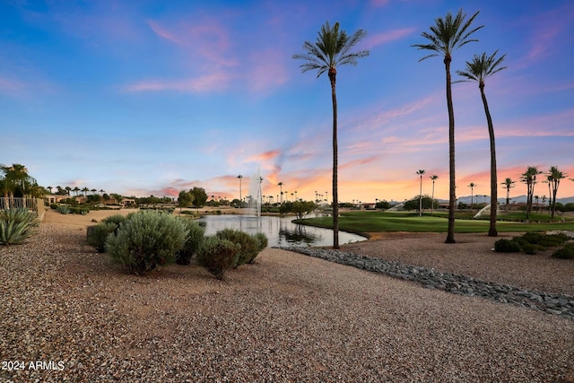 yard at dusk featuring a water view