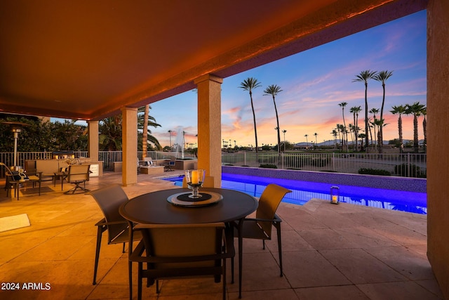 pool at dusk with a water view and a patio area