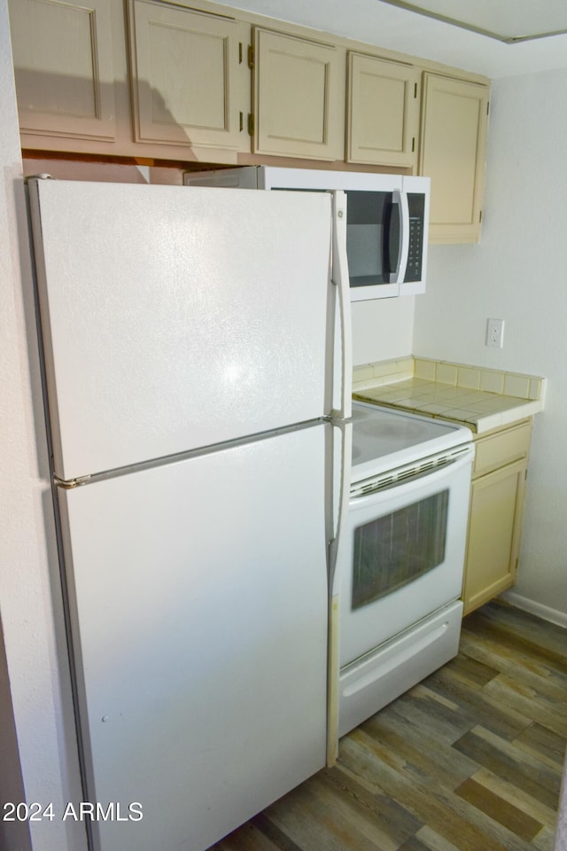 kitchen with cream cabinets, dark hardwood / wood-style flooring, and white appliances