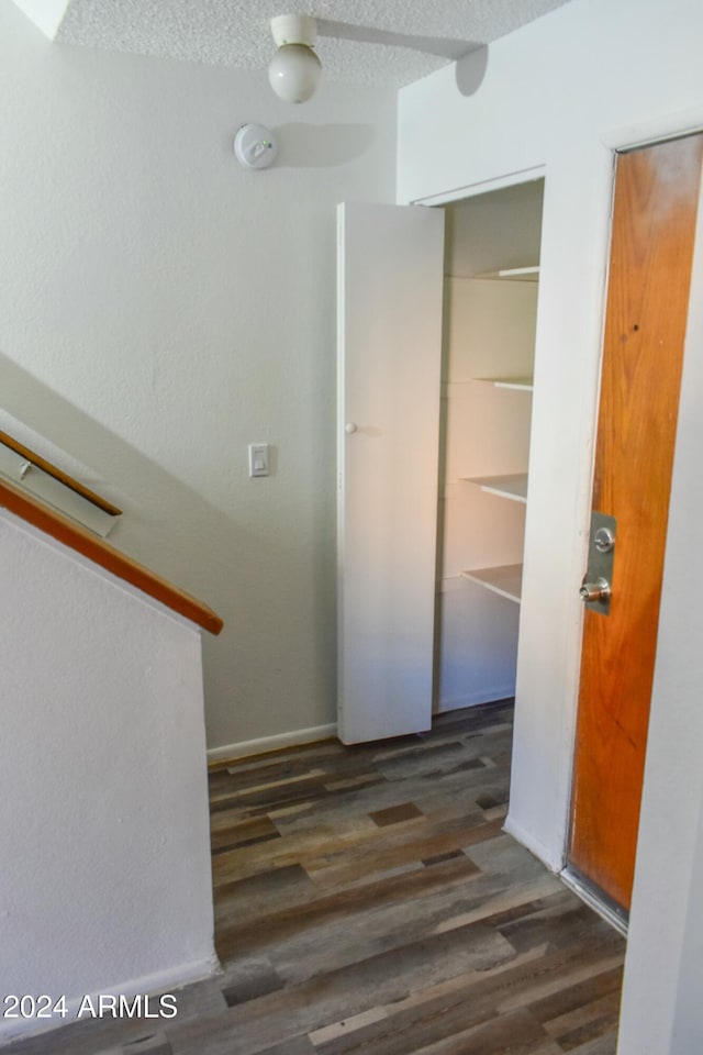 hallway with a textured ceiling and dark hardwood / wood-style floors