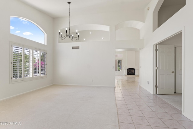 19010 N 35th Way, Phoenix, AZ 85050 - empty room with a towering ceiling, light tile patterned floors, a chandelier, a fireplace with raised hearth, and baseboards