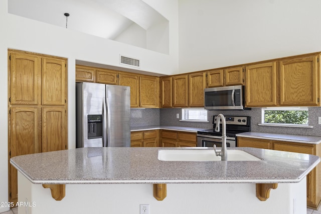 19010 N 35th Way, Phoenix, AZ 85050 - kitchen with stainless steel appliances, brown cabinets, a breakfast bar area, backsplash, and high vaulted ceiling