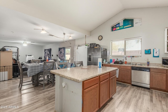 kitchen with a kitchen island, appliances with stainless steel finishes, lofted ceiling, and light wood-type flooring