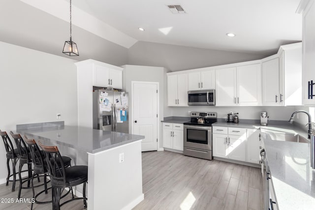 kitchen featuring a kitchen bar, sink, white cabinetry, appliances with stainless steel finishes, and kitchen peninsula