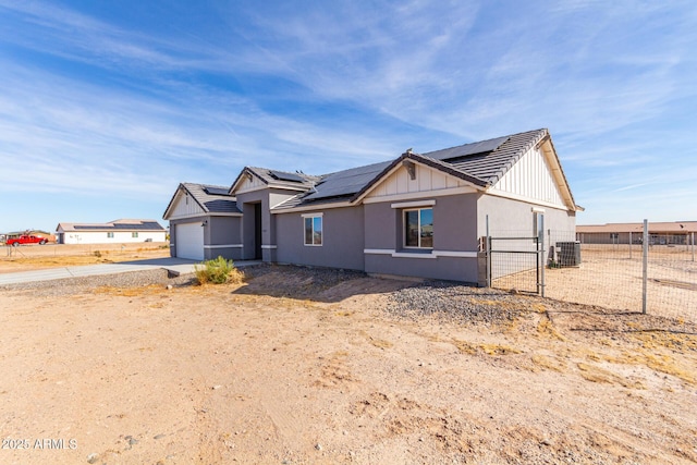 view of front of house featuring central AC, a garage, and solar panels