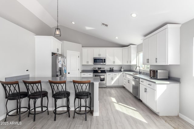 kitchen featuring white cabinetry, appliances with stainless steel finishes, sink, and decorative light fixtures