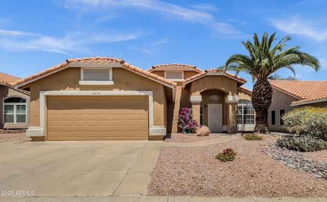 mediterranean / spanish home featuring concrete driveway, a tiled roof, an attached garage, and stucco siding