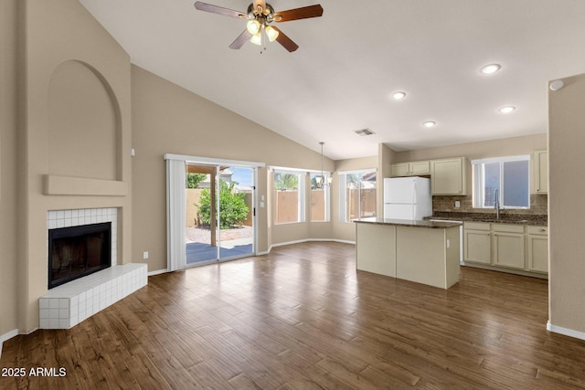 unfurnished living room featuring visible vents, a sink, dark wood-style flooring, high vaulted ceiling, and a ceiling fan
