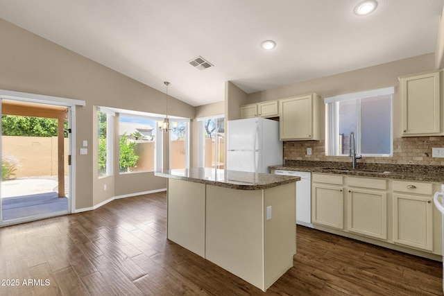 kitchen featuring visible vents, decorative backsplash, white appliances, a sink, and vaulted ceiling