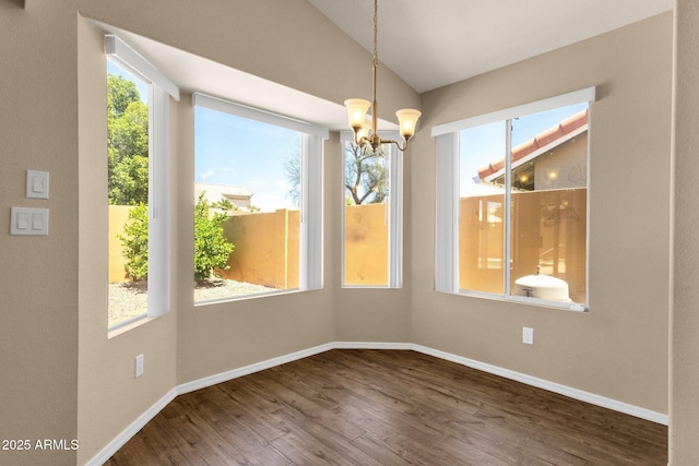 unfurnished dining area with baseboards, a notable chandelier, wood finished floors, and vaulted ceiling