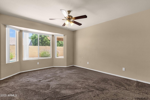 spare room with baseboards, a ceiling fan, and dark colored carpet