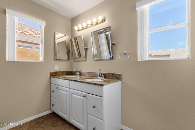 bathroom featuring a sink, baseboards, tile patterned floors, and double vanity