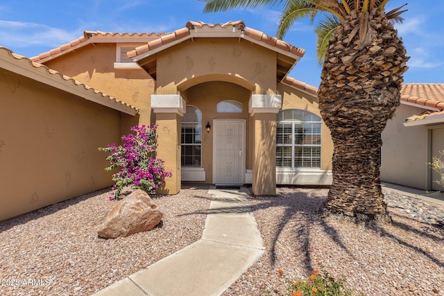property entrance with stucco siding and a tile roof