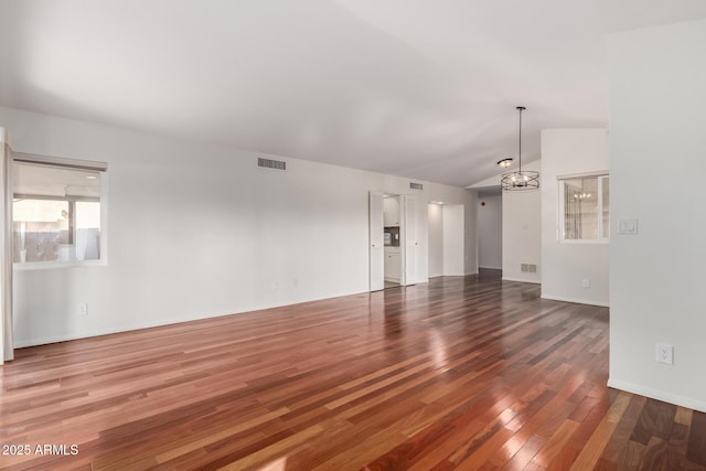 unfurnished room featuring visible vents, vaulted ceiling, a notable chandelier, and wood finished floors