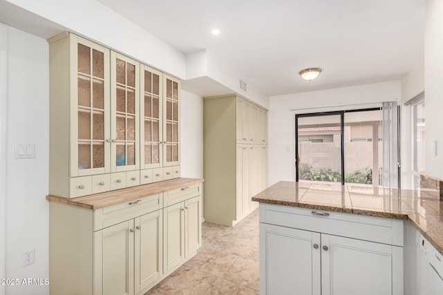 kitchen with butcher block counters, visible vents, glass insert cabinets, dishwasher, and a peninsula