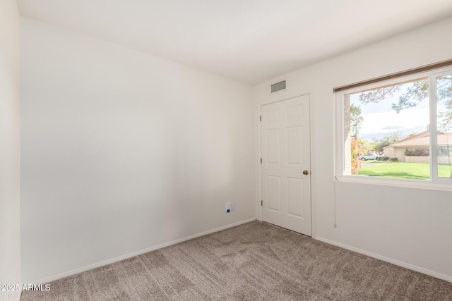 empty room with carpet floors, visible vents, and baseboards